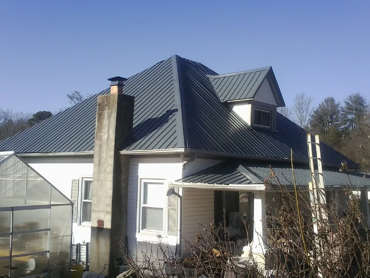 Dark blue standing seam metal roof on a white farmhouse with dormer — Slate & Tile Roof Repair by Roofing Brothers in Onslow