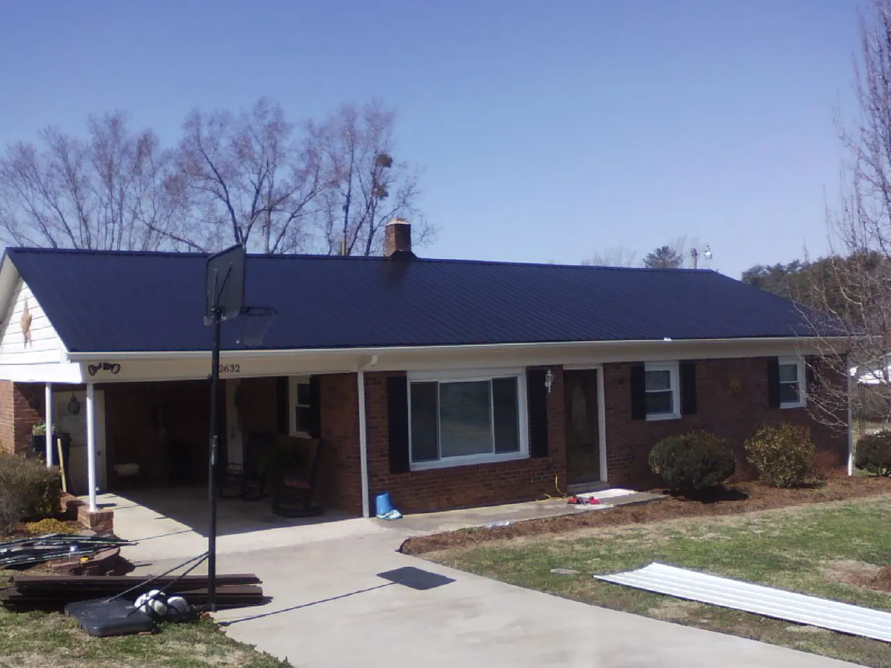 Finished dark blue metal roof on a brick ranch with a carport in Onslow