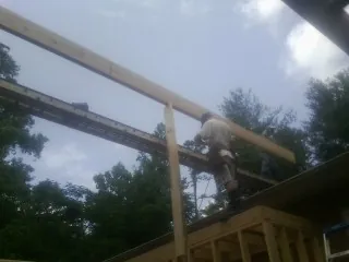 Carpenter setting a ridge beam over a new addition frame — Ice Dam Removal by Roofing Brothers in Onslow