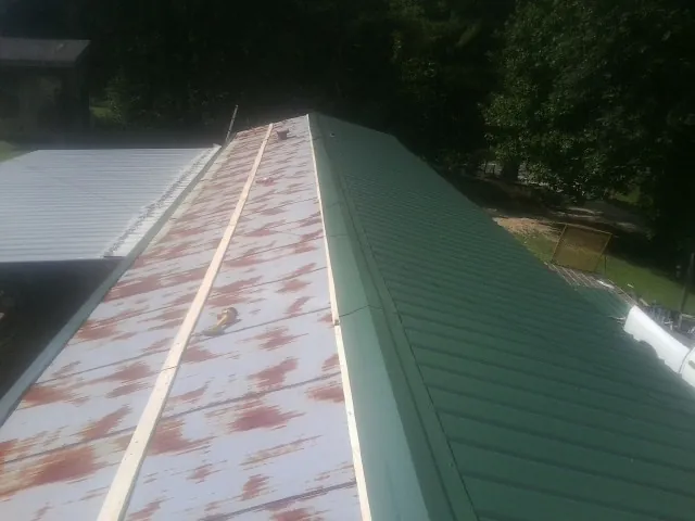 Old rusted panels beside newly installed green metal roofing — Wind Damage Roof Repair by Roofing Brothers in Onslow