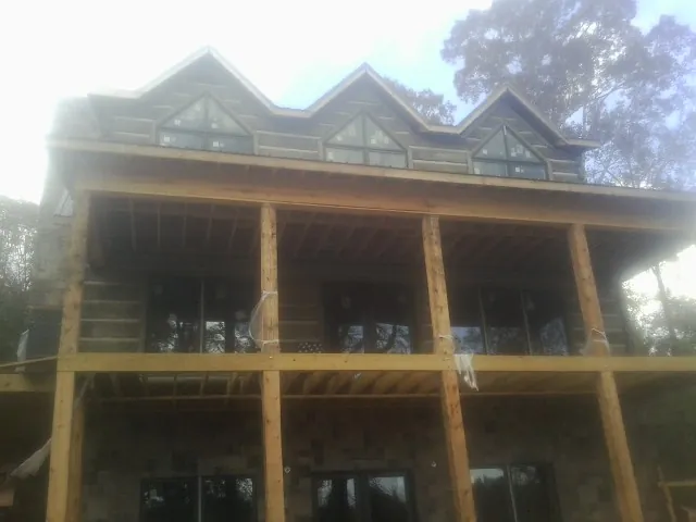 Dormers and porch framing on a large log home under construction — Roof Coating work by our crew in Onslow
