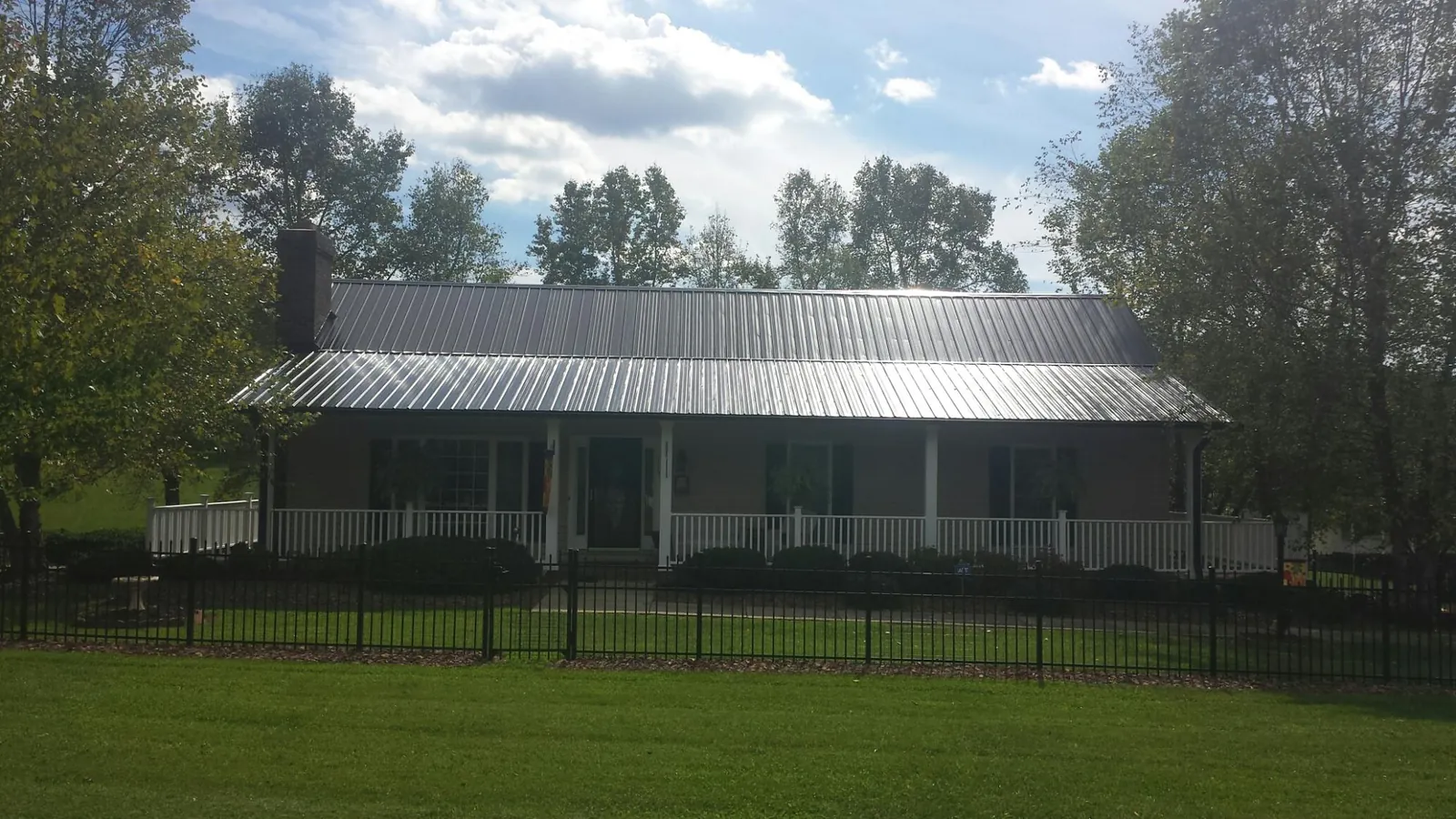 Gray metal roof on a brick ranch with a full width front porch — Gutter Guard Installation work by our crew in Onslow